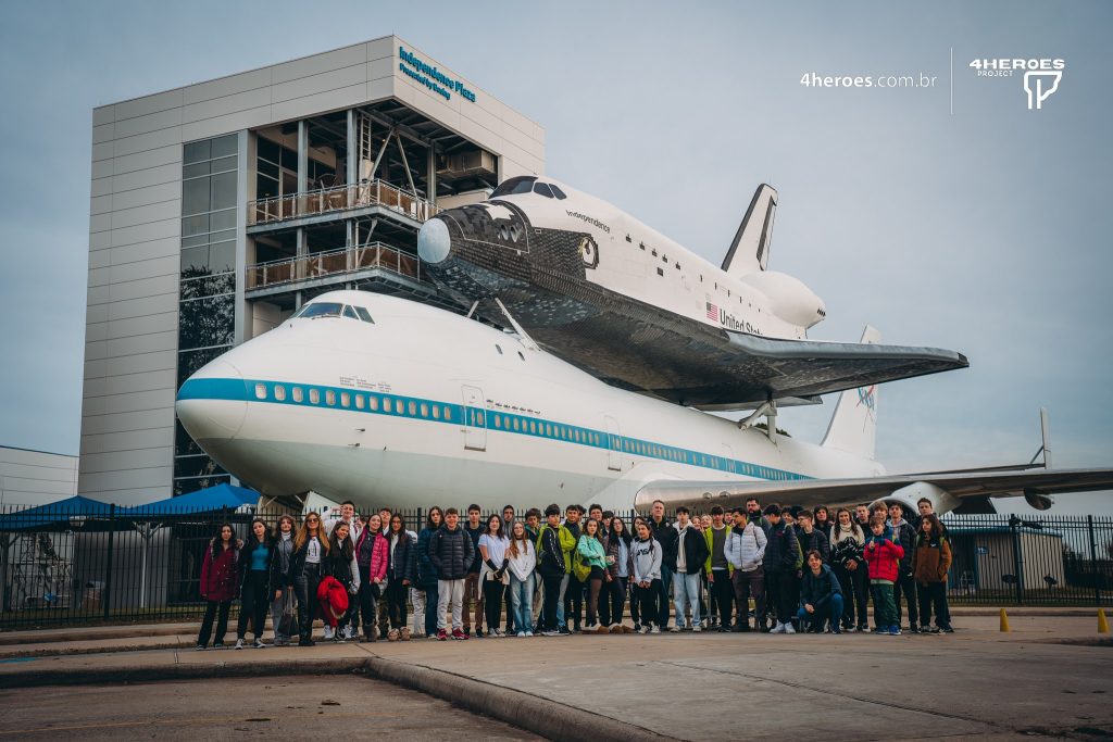 Grupo de participantes 4Heroes diante do ônibus espacial em Houston